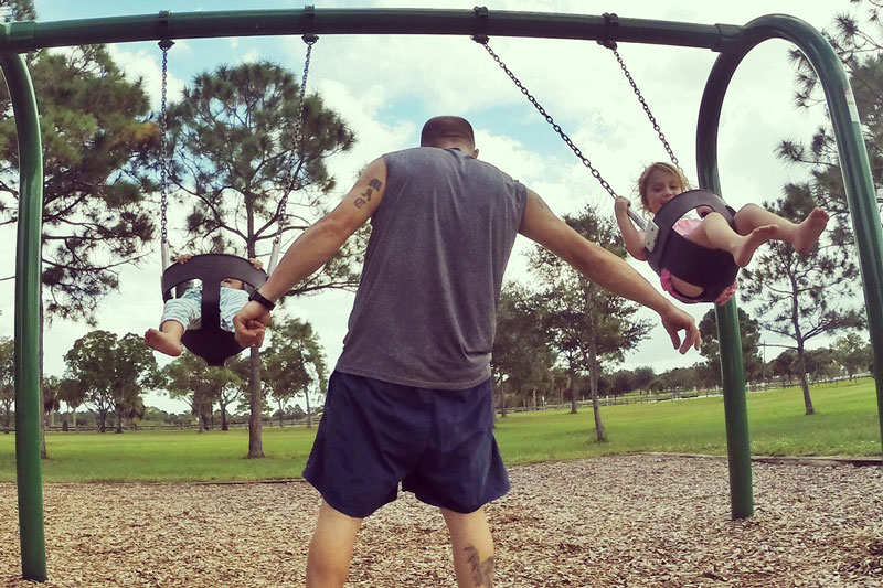 Dad pushing kids on swing