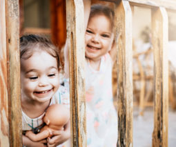 Two young girls laughing and looking through balcony railing - feature