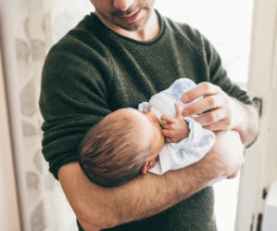 Father holding newborn baby feeding with a bottle - feature