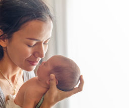 Mother holding newborn baby up close - feature
