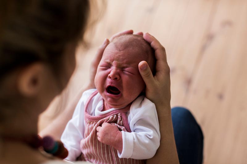 Newborn baby crying in mother's hands