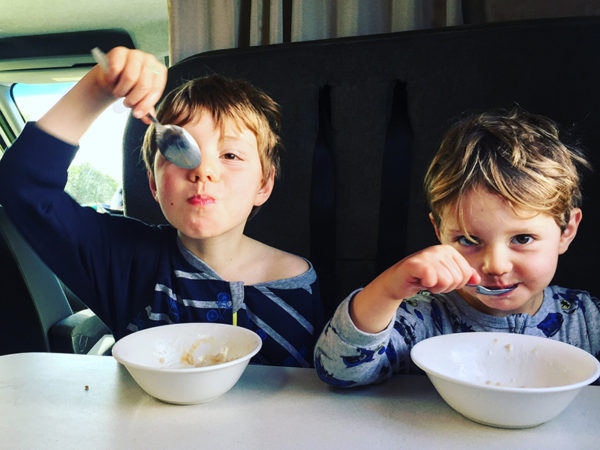 Two boys eating breakfast in a campervan