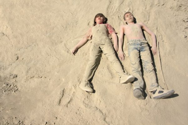 children playing dead in sand