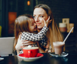 Mother sitting with daughter cafe drinking coffee hot chocolate - feature