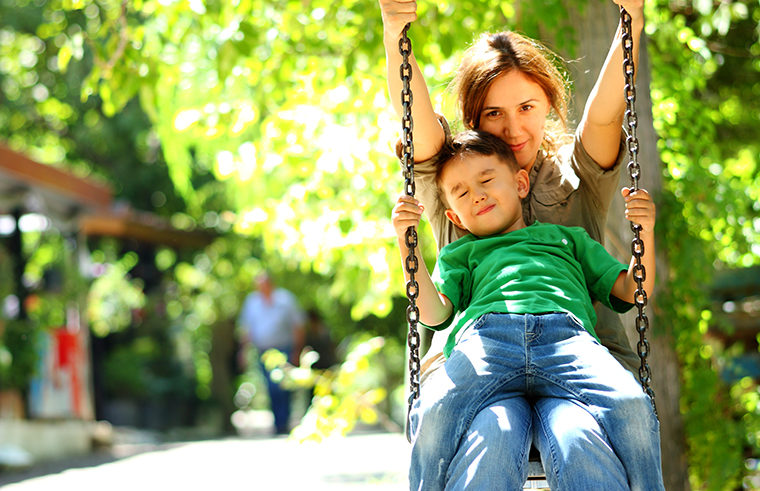 Mother and son on swing at park - feature