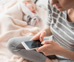 Mother using mobile phone while baby sleeps - feature