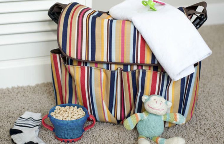 Stripy nappy bag with food, toys and products around the bag