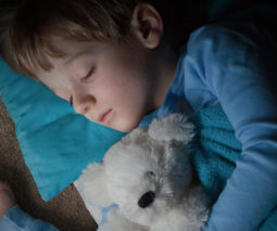 Older child asleep in bed with teddy bear