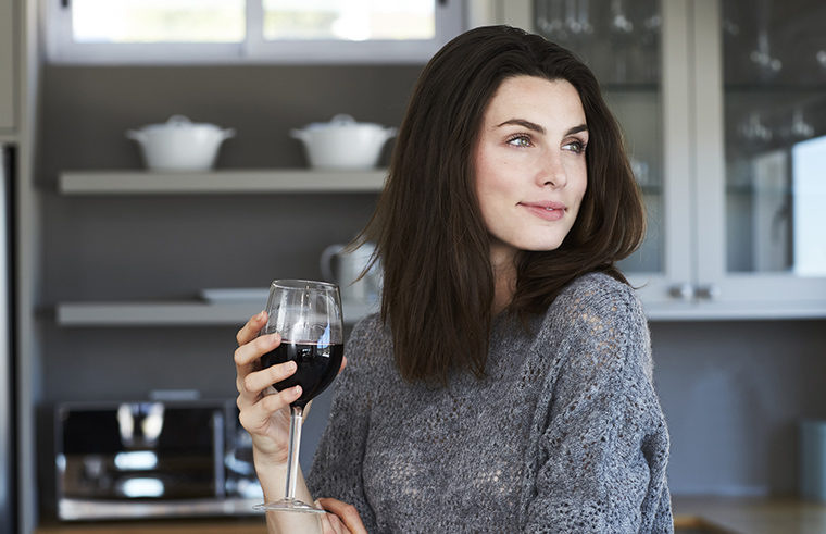 Woman drinking wine in kitchen - feature