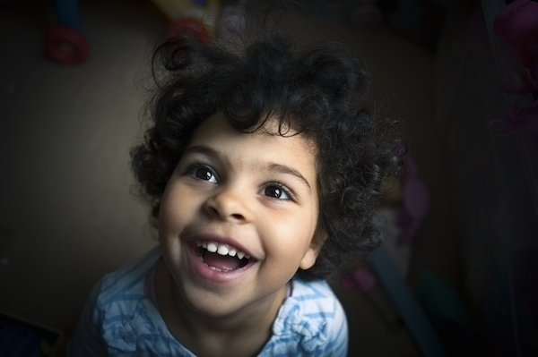 Portrait of a little girl of 3 years old taken overhead with a wide angle lens. Capturing her ecstatic happy toothy smile. This file has a signed model release.