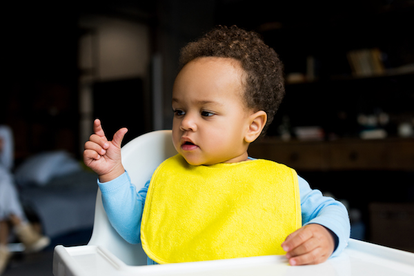 little african american boy with yellow bib sitting in baby chair