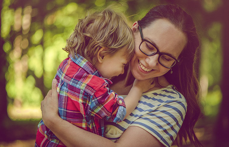 Mother cuddling toddler boy in plaid shirt - feature