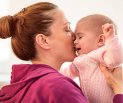 Mother holding baby kissing her face - feature