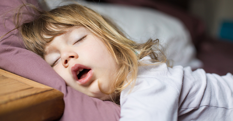 Toddler girl asleep in bed with mouth open