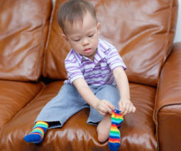 Toddler boy putting socks on - feature