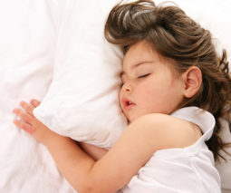 Toddler girl asleep in white bed - feature