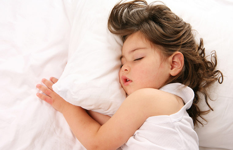 Toddler girl asleep in white bed - feature