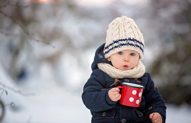 Toddler in winter with beanie and coat on holding mug - feature