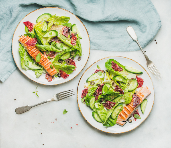 Healthy energy boosting spring salad with grilled salmon, blood orange, olives and quinoa, top view, marble background. Clean eating, dieting, detox, weight loss concept