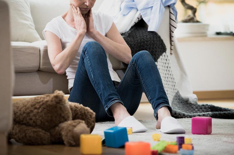 Frustrated mum sitting on floor with toys