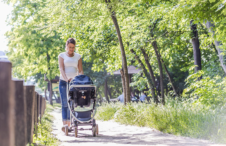 Mother pushing pram on footpath - feature