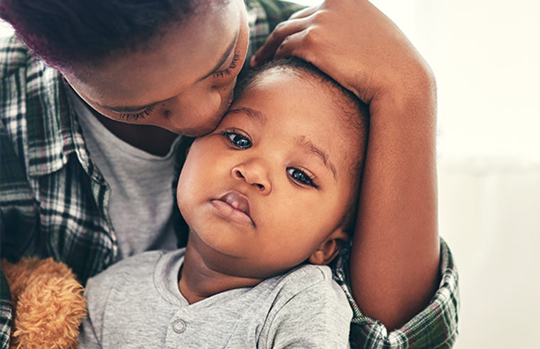 Black mother holding sick, sad toddler