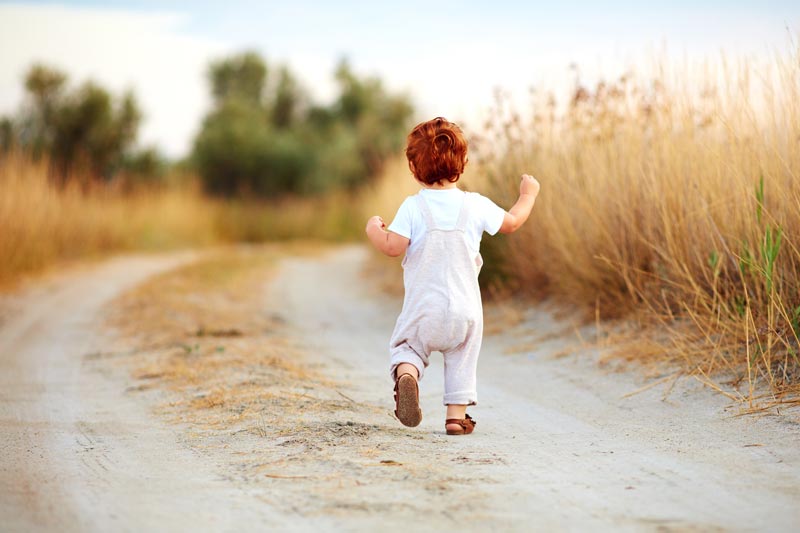Toddler running in field red hair