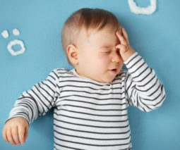 Upset baby with headache touching head- feature