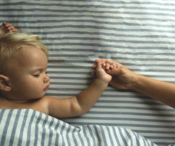 Sleeping baby holding mother's hand - feature