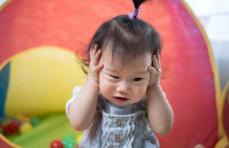 Asian toddler girl holding her head