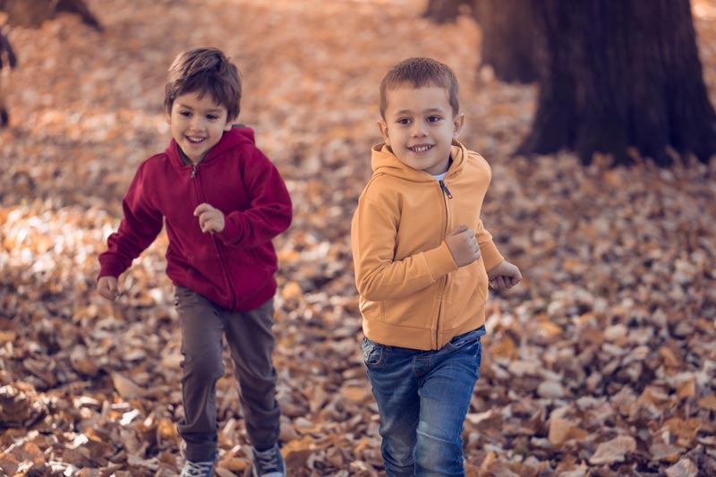 Boys running in autumn leaves