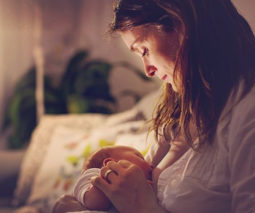 Mother breastfeeding newborn baby in a dim room