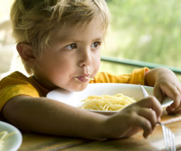 Young boy eating bowl of plain pasta - feature