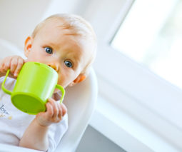 Baby in highchair drinking from sippy cup - feature