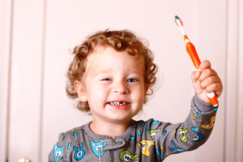 Boy wearing pyjamas holding toothbrush