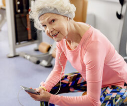 Grandmother holding mobile phone in the gym - feature