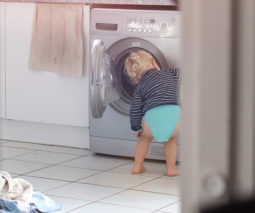 Toddler reaching into washing machine - feature