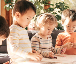 Toddlers drawing on paper with crayons - feature