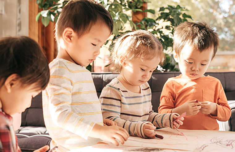 Toddlers drawing on paper with crayons - feature