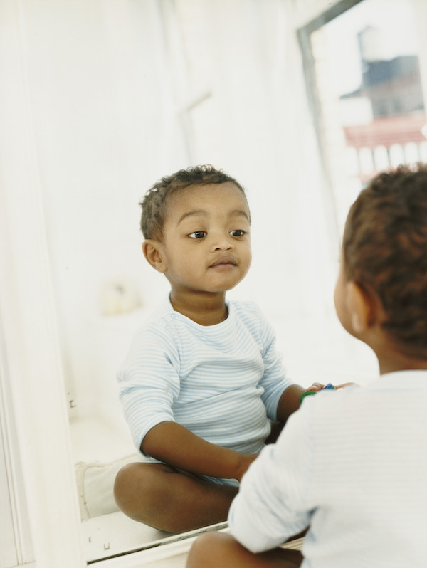 Young Boy Sitting in Front of a Mirror Looking at His Reflection