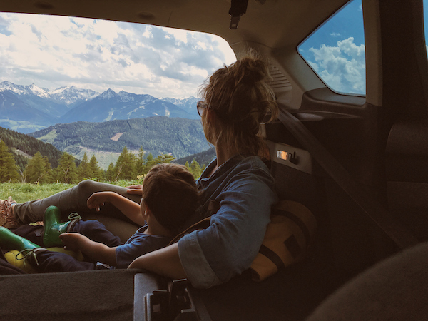 Mother and son enjoying the view of mountains from the car trunk