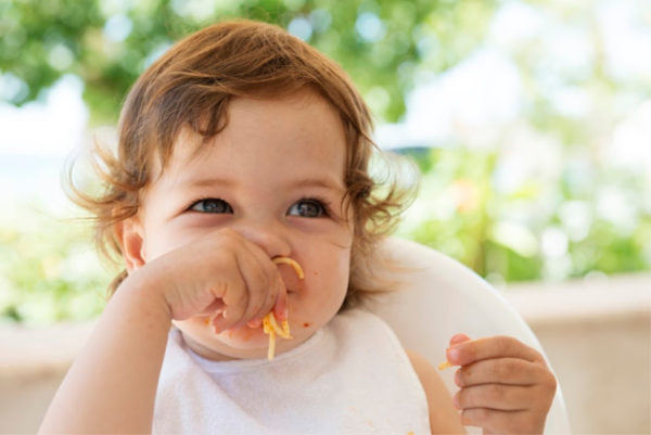 Baby girl eating pasta