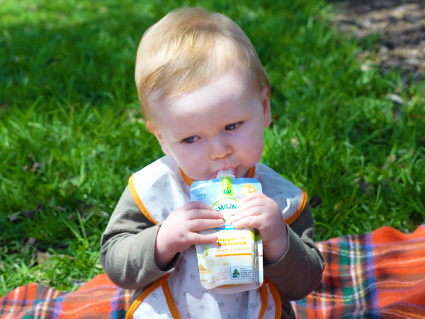 Baby eating from a Smiling Tums baby food pouch