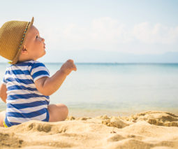 Baby boy sitting at the beach - feature