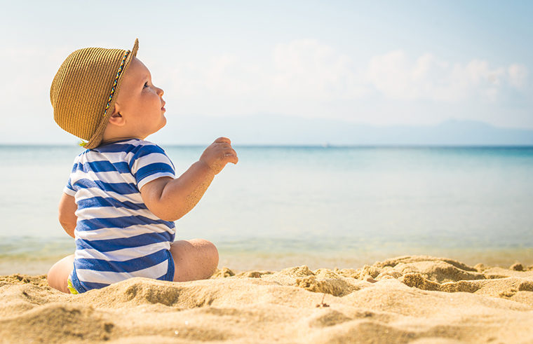 Baby boy sitting at the beach - feature