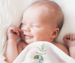 Smiling sleeping baby on soft, fluffy blanket - feature
