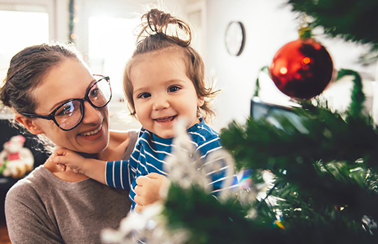 Mother holding toddler at Christmas tree - feature