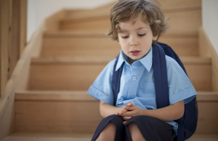 School boy sitting on stairs with backpack- feature