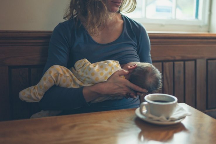 Mother breastfeeding and drinking coffee