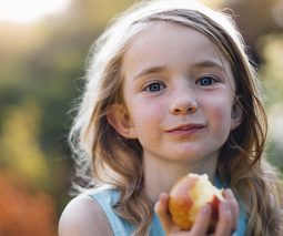 Happy girl eating an apple outdoors